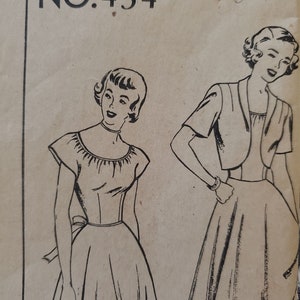 May include: A vintage sewing pattern envelope labeled NO. 434 featuring black ink line drawings of two outfits. One shows a dress with a gathered neckline and waist tie, while the other displays a dress paired with a short-sleeved cropped jacket.