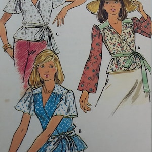 Op de afbeelding: Illustratie van drie wikkelblouses met striksluitingen. De blouses hebben bloemen- en stippenpatronen in verschillende kleuren, waaronder wit, blauw en rood. De afbeelding is een vintage naaipatroon.