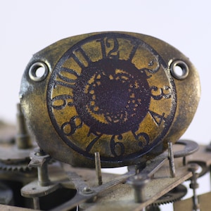 May include: Close-up of a gold-colored clock face with black Roman numerals and a dark brown center. The clock face is attached to a complex, intricate, and aged metal mechanism.