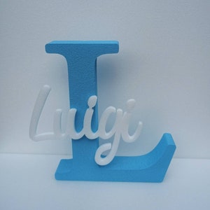 Könnte beinhalten: Ein hellblauer Holzbuchstabe L mit dem Namen Luigi in weißen Kursivbuchstaben.