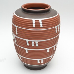 May include: A brown ceramic vase with white drip-like designs. The vase has a ribbed texture and a dark brown rim.