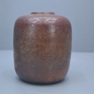 Può includere: Un piccolo vaso rotondo in ceramica marrone con una superficie testurizzata.