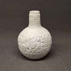 May include: White ceramic vase with a textured, pebble-like surface.