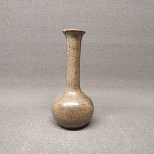 Puede incluir: Un pequeño jarrón de cerámica marrón moteado con una base redonda y un cuello estrecho.