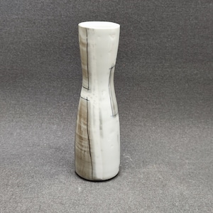 Può includere: Un vaso in ceramica bianca con un design geometrico marrone e nero. Il vaso ha un collo stretto e una base larga.