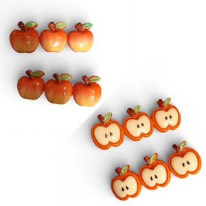 Pode incluir: Uma coleção de ornamentos decorativos em forma de maçã. Os ornamentos são em dois estilos: maçãs inteiras e metades de maçã. As maçãs inteiras são laranja e vermelhas com folhas verdes. As metades de maçã são laranja com interior creme.