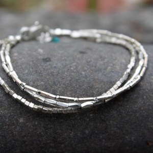 Puede incluir: Un brazalete de plata con tres filas de pequeñas cuentas rectangulares.