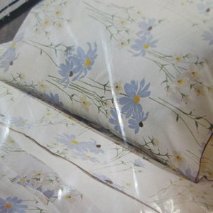 May include: A white bedding set with a floral pattern featuring blue and yellow flowers. The bedding set includes a fitted sheet, flat sheet, and pillowcase.