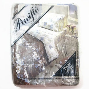 May include: A packaging for a twin-sized Daisy Days bedding set with a floral pattern. The packaging is labeled "Pacific" and features a white wicker bed with a floral patterned comforter and pillow.