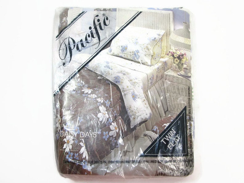 May include: A packaging for a twin-sized Daisy Days bedding set with a floral pattern. The packaging is labeled "Pacific" and features a white wicker bed with a floral patterned comforter and pillow.