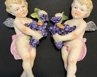 Pareja de querubines de Napco, ángeles sosteniendo uvas para colgar en la pared.