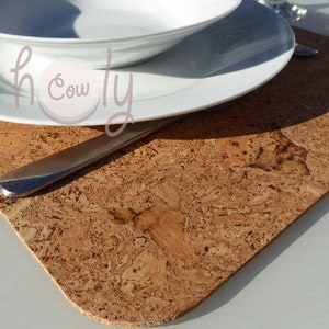 Könnte beinhalten: Ein quadratischer Korkuntersetzer mit einem braunen und beigefarbenen Marmormuster. Ein weißer Teller und eine Schüssel liegen auf dem Untersetzer, daneben ein silbernes Messer.