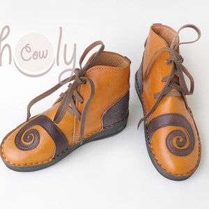 K&ouml;nnte beinhalten: Leder-Ankle-Boots in Braun- und Beiget&ouml;nen. Die Schuhe haben ein Spiralmuster auf der Zehenpartie und einen dunkelbraunen Einsatz an der Ferse. Braune Schn&uuml;rsenkel und ein Rei&szlig;verschluss. Geeignet f&uuml;r den t&auml;glichen Gebrauch.
