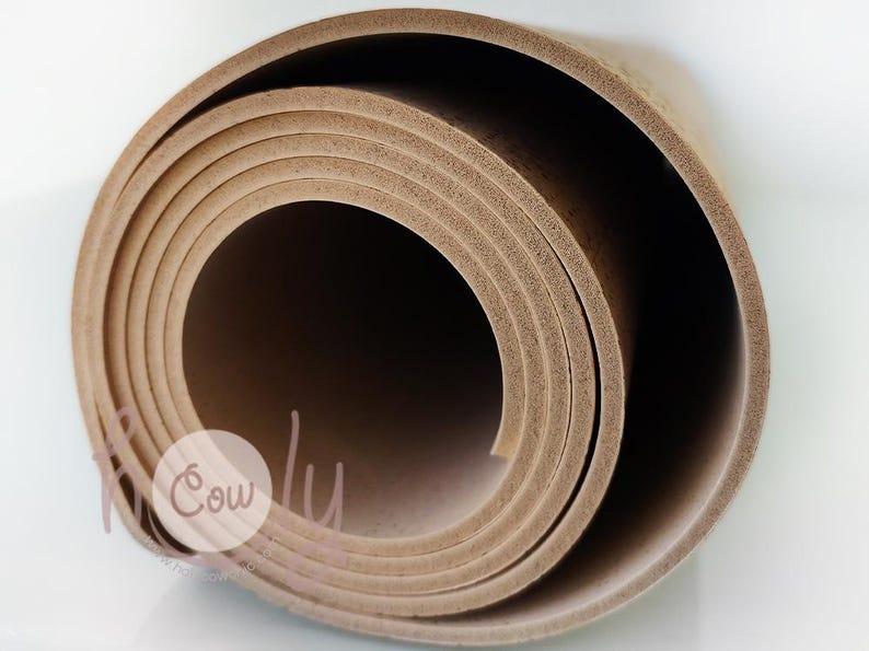 Op de afbeelding: Opgerolde bruine yogamat. De mat is gemaakt van een textuurrijk materiaal en is opgerold in een spiraalvorm. De mat ligt op een witte ondergrond. Het Cowly-logo is zichtbaar in de linker benedenhoek.