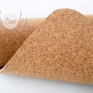 May include: A close-up of a roll of cork fabric. The fabric is a natural brown color and has a textured surface.