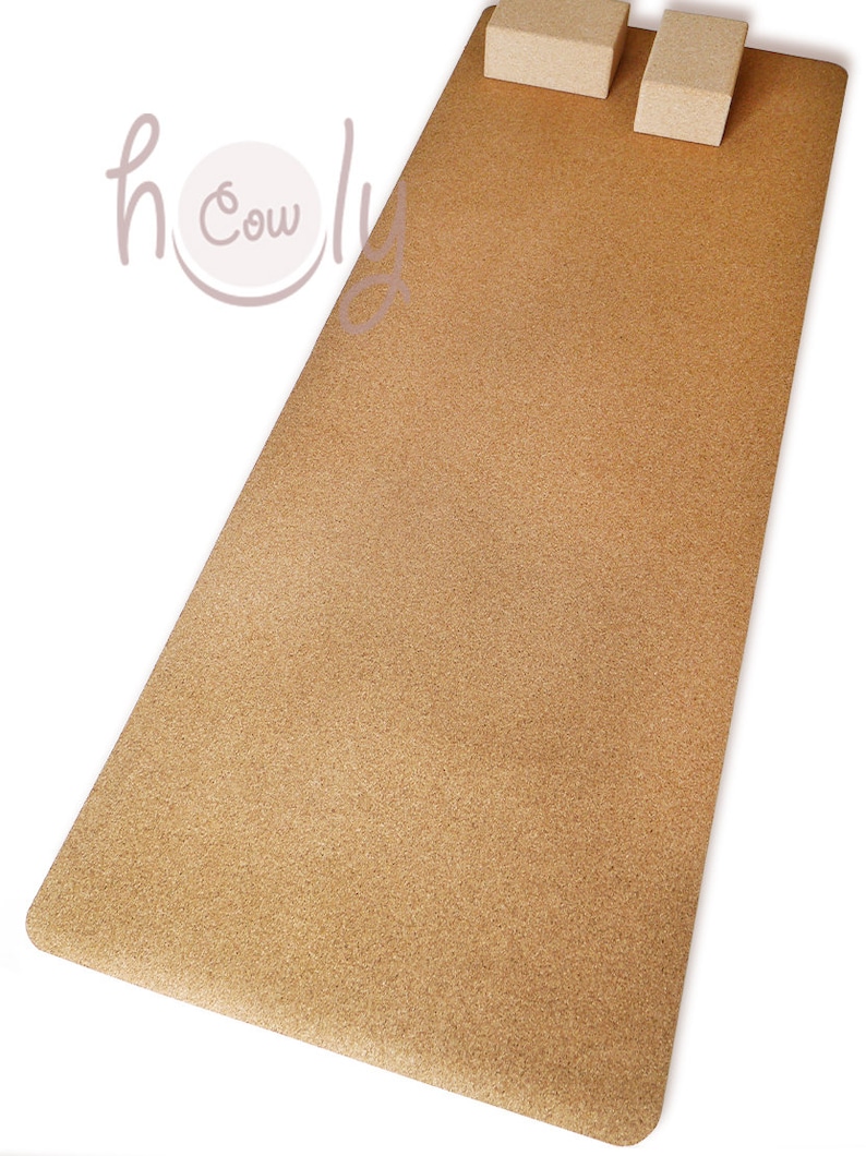 May include: A light brown cork yoga mat with two light brown cork blocks on top. The mat is textured and has a slightly rough surface.