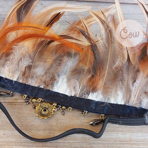 Puede incluir: Una diadema negra adornada con plumas marrones y beige. La diadema presenta una pieza central floral dorada y colgantes. Las plumas est&aacute;n dispuestas en forma de abanico, creando un efecto visual llamativo. Este accesorio es adecuado para eventos tem&aacute;ticos.