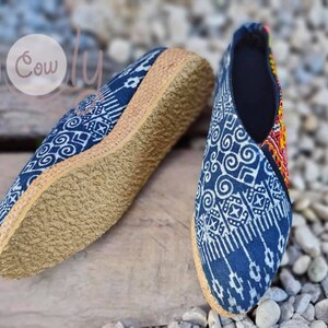 K&ouml;nnte beinhalten: Ein Paar blaue und wei&szlig;e, gemusterte Slipper mit einem Obermaterial aus gewebtem Stoff und einer nat&uuml;rlichen Jutesohle.
