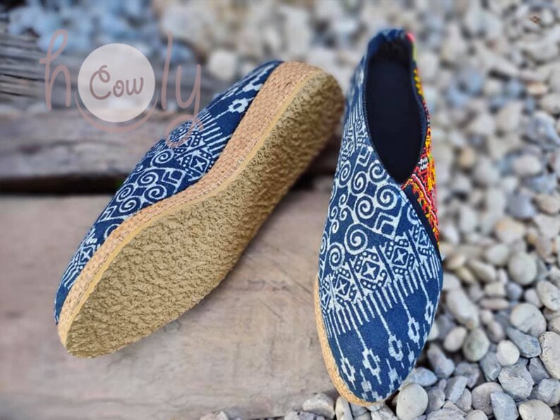 K&ouml;nnte beinhalten: Ein Paar blaue und wei&szlig;e, gemusterte Slipper mit einem Obermaterial aus gewebtem Stoff und einer nat&uuml;rlichen Jutesohle.