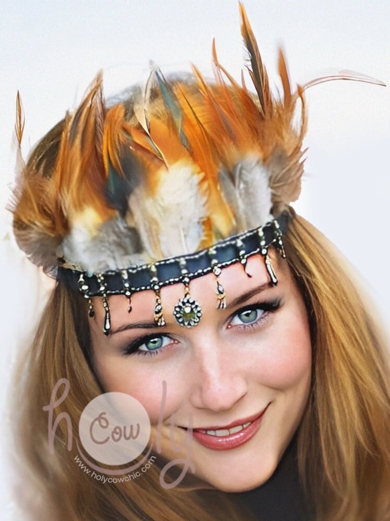Puede incluir: Tocado decorativo con una banda negra adornada con colgantes dorados y un adorno floral central. Est&aacute; rematado con una corona de plumas marrones, naranjas y grises, creando una est&eacute;tica bohemia.