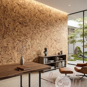 May include: A room featuring a large wall covered in textured brown cork tiles, a dark wood desk with a black metal frame, a low wooden bookshelf, a leather armchair with an ottoman, and a light-colored floor with the text "holy Cow" visible.