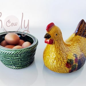 May include: A ceramic chicken figurine with brown and yellow feathers and a red comb. The chicken is holding a green ceramic basket filled with brown eggs.