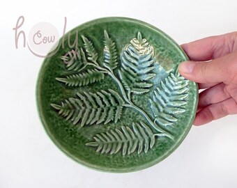 May include: A green ceramic dish with a fern design. The dish is embossed with a fern pattern and has a slightly textured surface.
