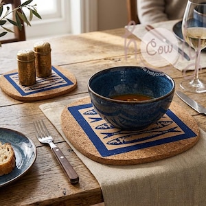 Könnte beinhalten: Ein gedeckter Tisch mit rustikaler Ästhetik. Es gibt eine blaue Keramikschüssel mit Suppe, Untersetzer aus Kork mit blauem Fischdesign und einen Teller mit Brot. Salz- und Pfefferstreuer sowie ein Weinglas sind ebenfalls vorhanden.