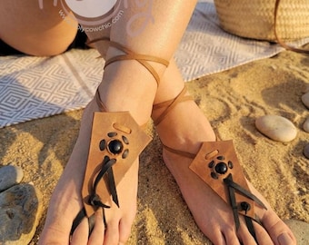 Sandalias descalzas de cuero hechas a mano, corte natural y terroso, adornadas con piedras negras.