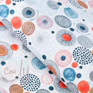 May include: White fabric with a repeating pattern of colorful, abstract circles. The circles vary in size and design, featuring orange, blue, and black accents. Some circles have dotted or lined details, creating a textured appearance. The fabric is folded, showing its layered texture.