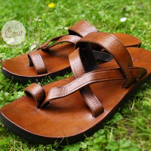 May include: A pair of brown leather sandals with multiple straps. The sandals have a toe loop and a thick sole.