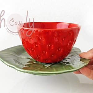 以下が含まれることがあります： イチゴの形をした赤いセラミックボウルと、葉の形をした緑色のセラミックソーサー。ボウルとソーサーはセットになっています。