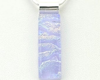 May include: A rectangular pendant necklace with a light purple, textured glass design. The pendant is suspended from a silver chain. The glass has a layered, wave-like pattern with iridescent highlights.
