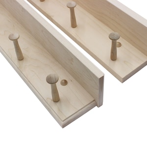 May include: Two wooden wall-mounted coat racks with multiple wooden pegs. The racks are made of natural wood and have a simple, minimalist design.