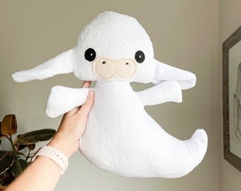 May include: White plush ghost toy with black eyes and a beige nose. The ghost has large, floppy ears and a long, flowing tail.