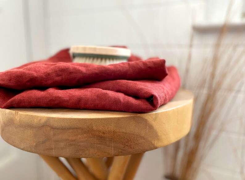 May include: A stack of red linen towels folded on a wooden stool.