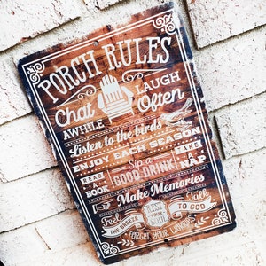 Può includere: Un cartello in legno rustico con il testo "Porch Rules" in lettere bianche. Il cartello elenca le regole per godersi il tempo su un portico, come "Chat Awhile", "Listen to the birds", "Enjoy Each Season", "Read a Book", "Sip a Good Drink", "Take a Nap", "Make Memories", "Feel the Breeze", "Rest Your Soul", "Talk to God" e "Forget Your Worries".