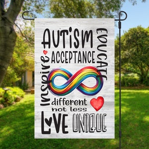 May include: A white wooden garden flag with the text "AUTISM EDUCATE INSPIRE ACCEPTANCE" and a rainbow infinity symbol. The text "different not less LOVE UNIQUE" is also on the flag.