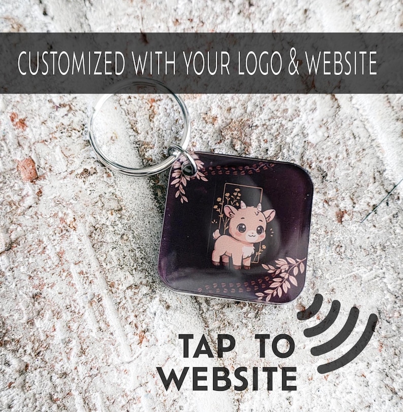 May include: A square keychain with a cartoon goat illustration on a dark purple background, accented with pink floral designs. The keychain has a silver ring and the text "CUSTOMIZED WITH YOUR LOGO & WEBSITE" and "TAP TO WEBSITE".