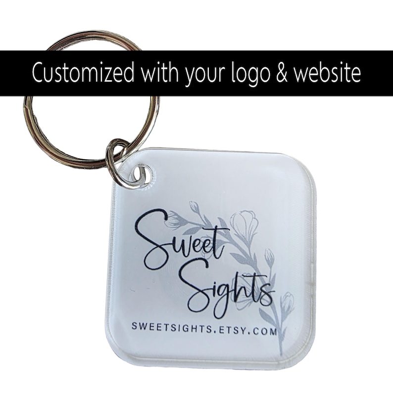 May include: Clear square keychain with a silver keyring. The keychain features the text "Sweet Sights" in black script with a floral design in grey. The website address, sweetsights.etsy.com, is printed below. The top of the image reads "Customized with your logo & website."