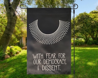 May include: Black garden flag with a white outline of a judge's collar and the text "With fear for our democracy, I dissent."