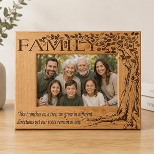 May include: A rectangular light brown wooden picture frame featuring an engraved tree design on the right side and the word FAMILY at the top. The bottom includes the engraved quote: like branches on a tree, we grow in different directions yet our roots remain as one.