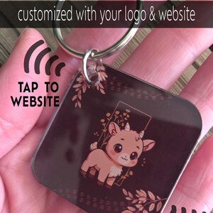 May include: A square keychain with a silver ring. The keychain has a dark brown background with a cartoon goat illustration. The text "customized with your logo & website" is at the top. The text "TAP TO WEBSITE" is on the left.