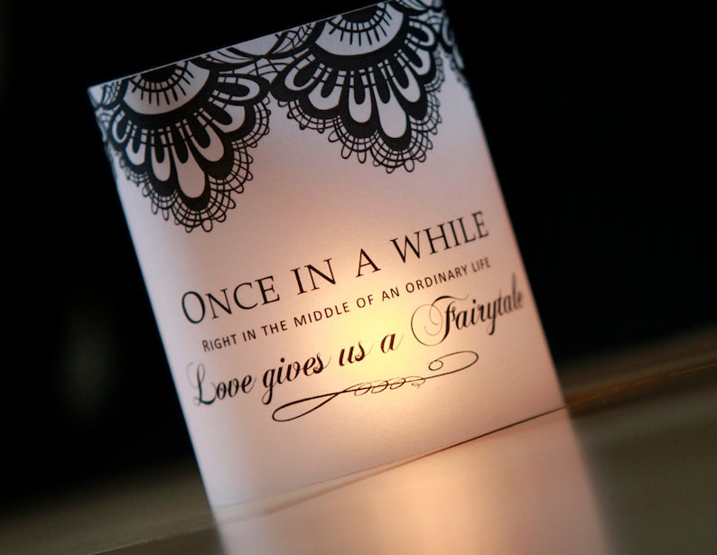 Op de afbeelding: Een witte kaart met zwarte kantversiering en de tekst "ONCE IN A WHILE RIGHT IN THE MIDDLE OF AN ORDINARY LIFE Love gives us a Fairytale".