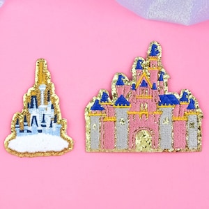 May include: Two embroidered patches featuring castle designs. One patch depicts a light blue and gold castle on a white cloud, while the other showcases a pink and gray castle with blue and gold accents. Both patches have gold glitter borders.
