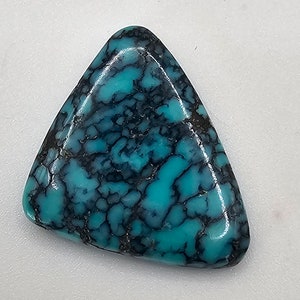 Può includere: Un cabochon di turchese triangolare di colore blu-verde con un motivo a matrice nera.