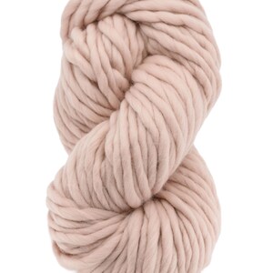 May include: A skein of light pink yarn, made of wool, is shown in a close-up view. The yarn is thick and fluffy, and it is perfect for knitting or crocheting.