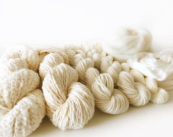 May include: A collection of white yarn skeins and balls of yarn. The yarn is soft and fluffy, perfect for knitting or crocheting.