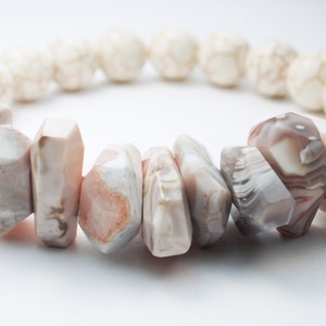 May include: A bracelet made of white and pink agate beads. The beads are faceted and have a natural, organic look.
