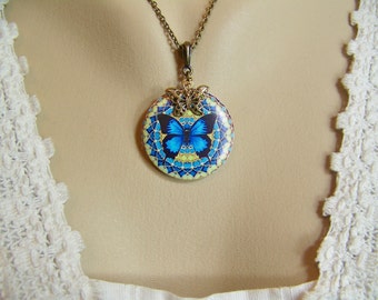 May include: A round pendant necklace featuring a blue butterfly on a yellow and blue mandala design. The pendant is attached to a bronze chain.